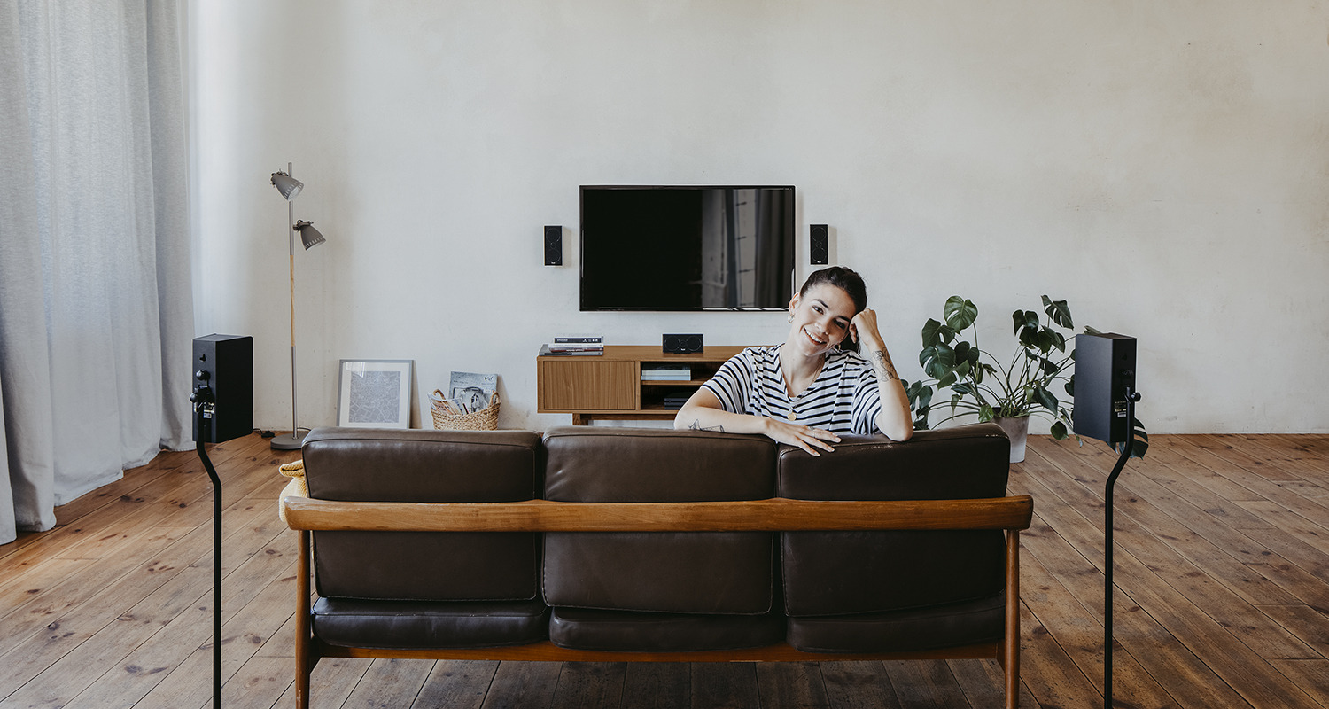 Frau im Wohnzimmer vor Heimkinoanlage.