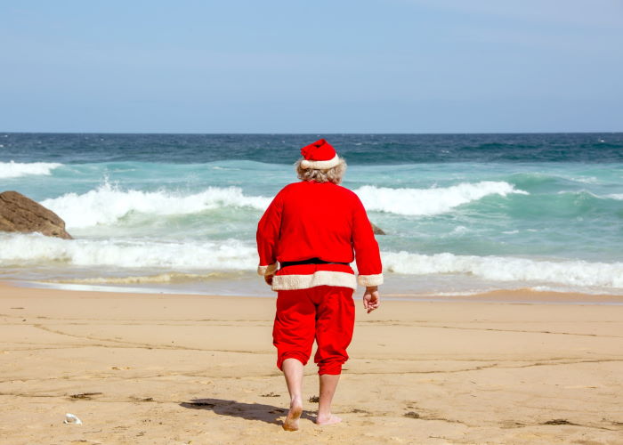 Rear view of a man dressed as Santa Clause on the beach
