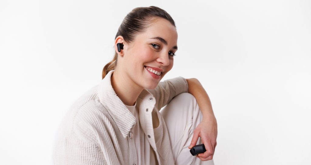 A young woman wears a black pair of AIRY TWS 2 headphones
